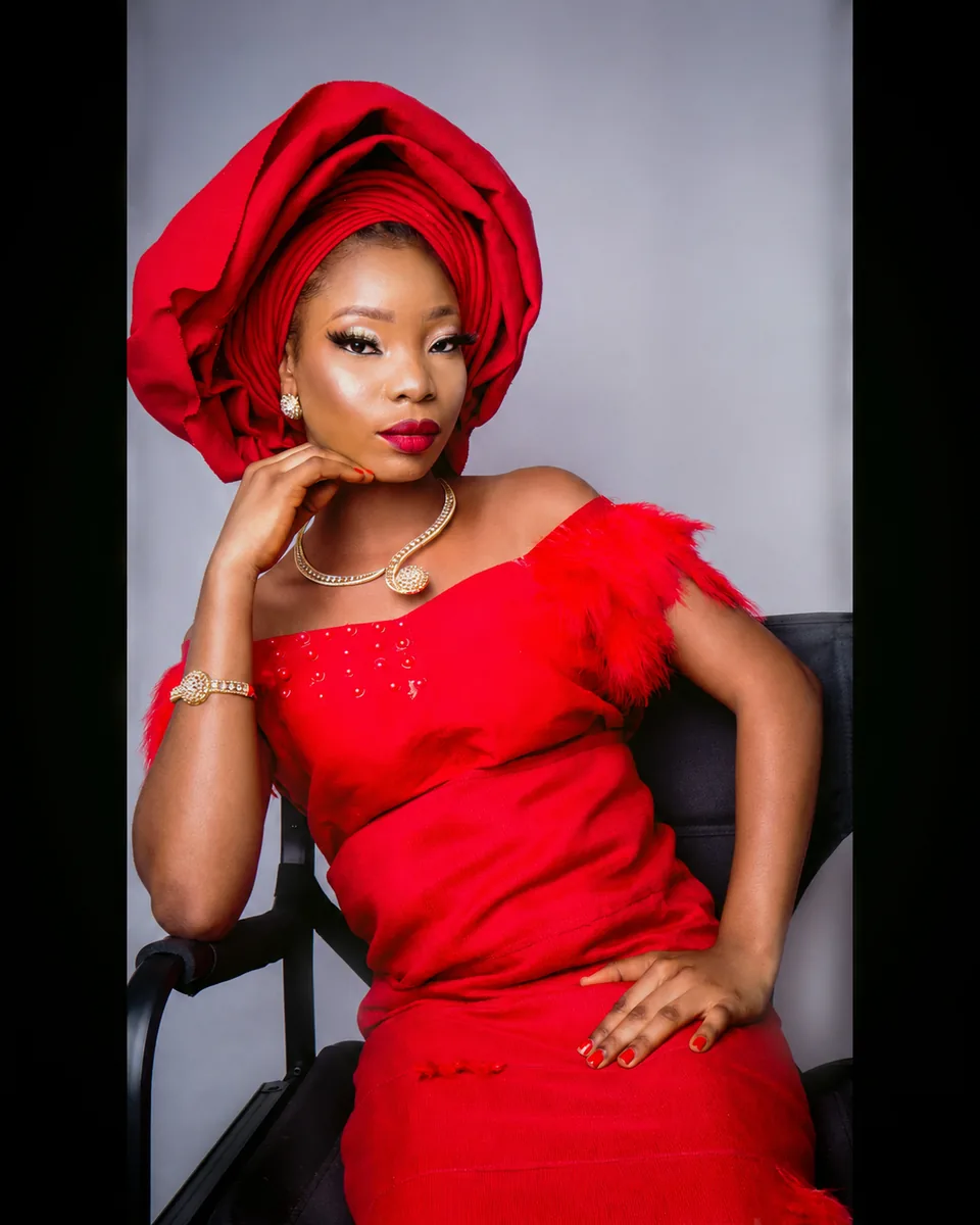 Cultural portrait of a woman in red traditional attire seated in a studio setting