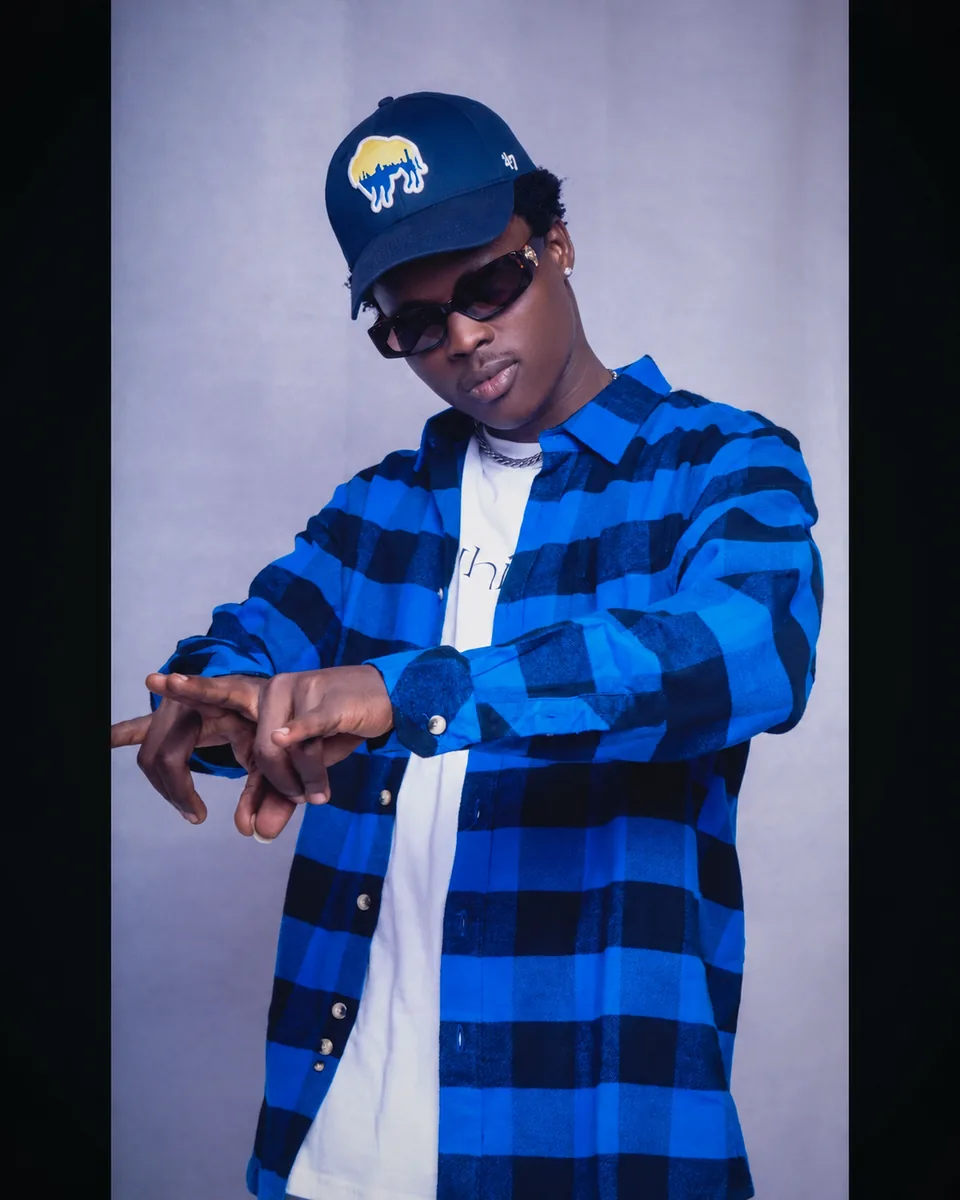Studio portrait of a male artist wearing sunglasses and a blue and black outfit