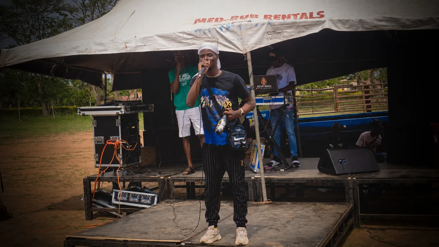 Live event photo of a performer holding a microphone on an outdoor stage